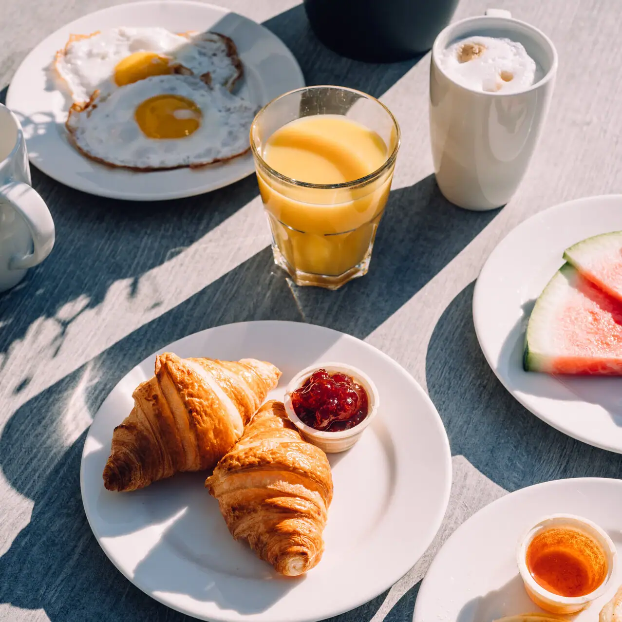 Croissants Een tafel met borden vol eten en drinken.