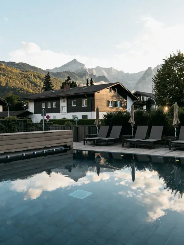 Buitenzwembad Een zwembad met stoelen en een gebouw op de achtergrond.