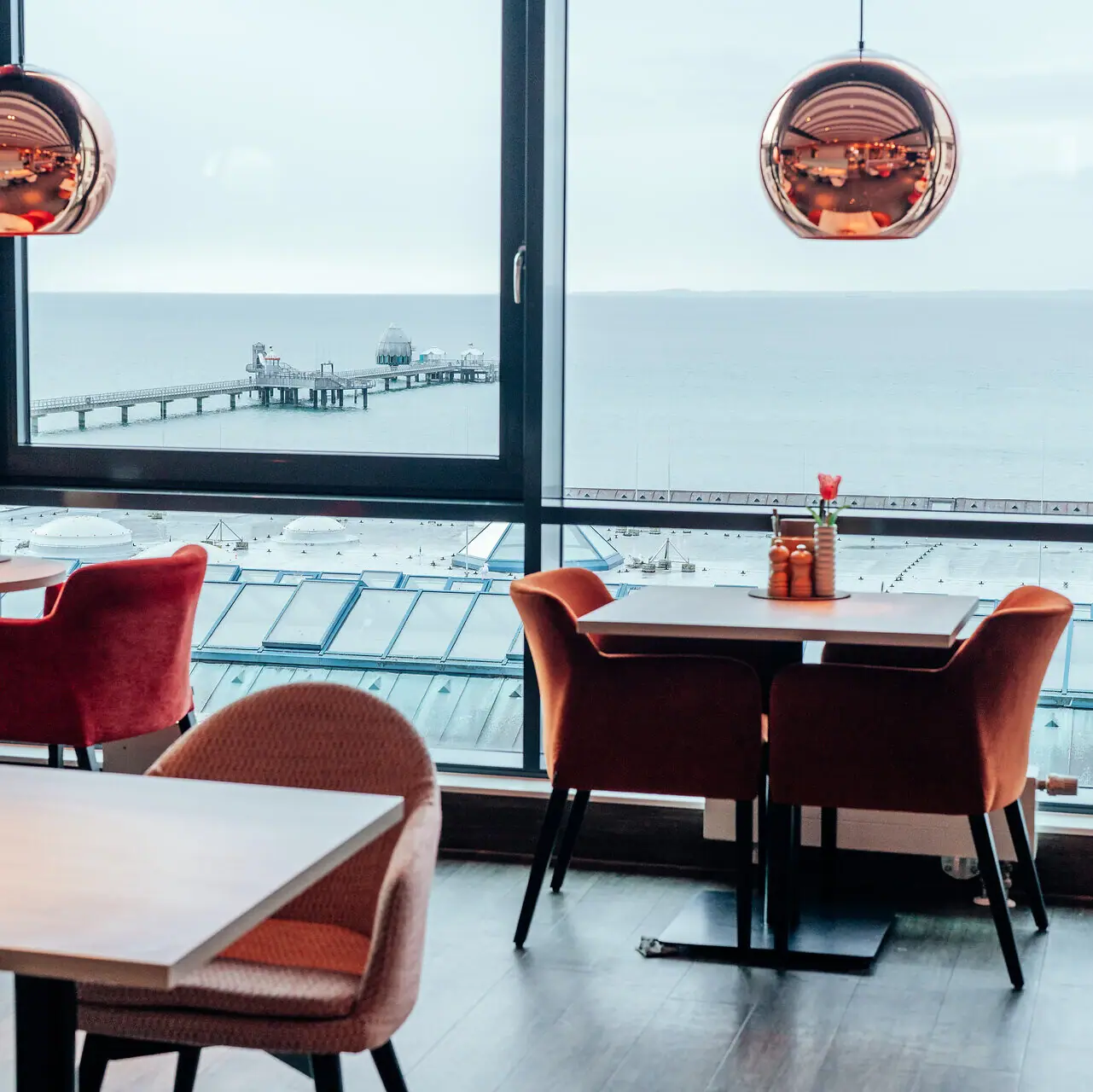 Een kamer met uitzicht op de oceaan en een pier, met een koffietafel en een keuken- en eettafel.