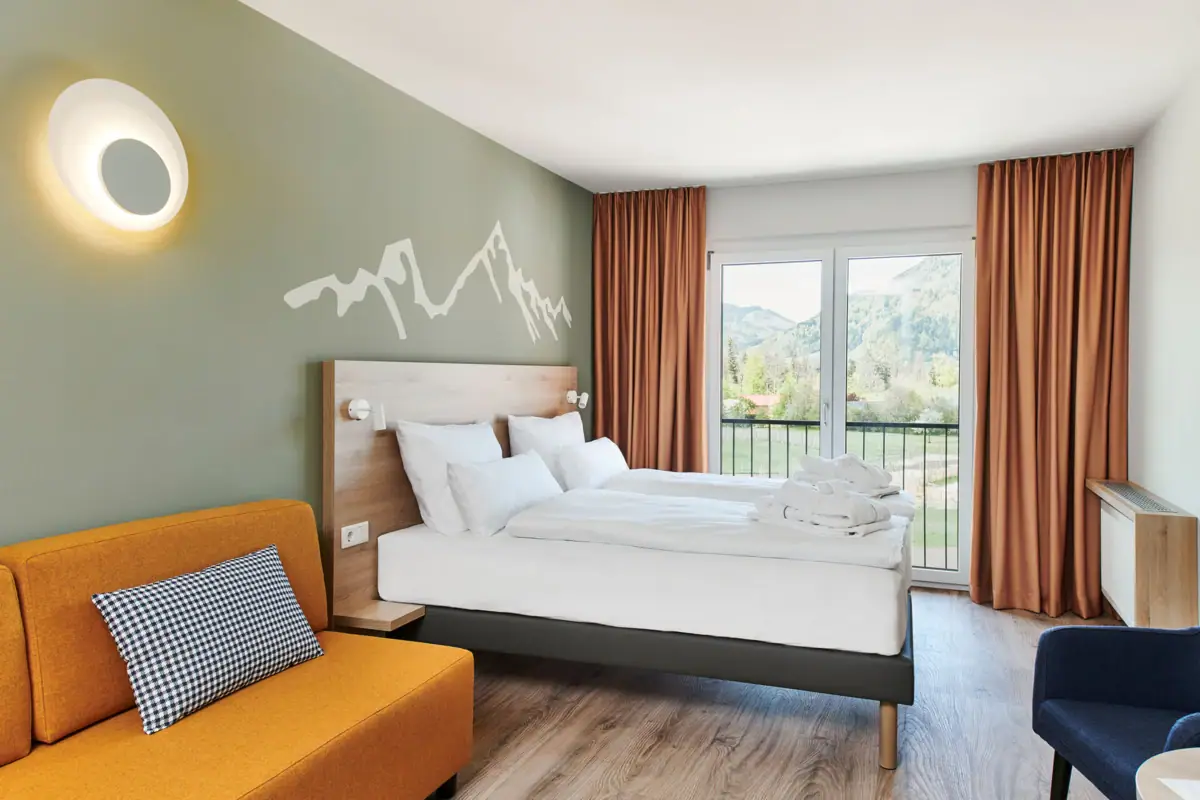 Een kamer met twee bedden en een bank.