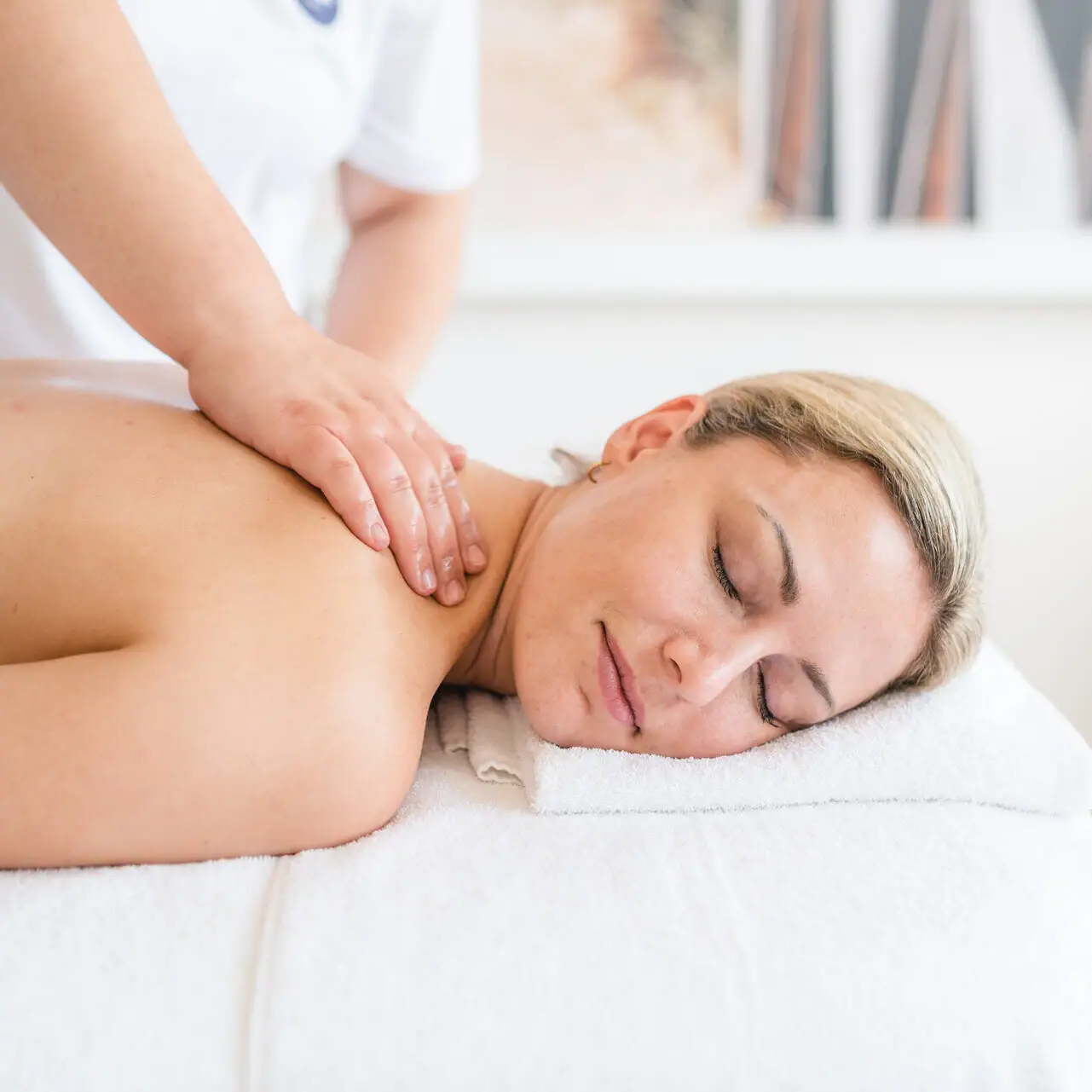 Een vrouw ligt op een witte handdoek met haar ogen dicht.