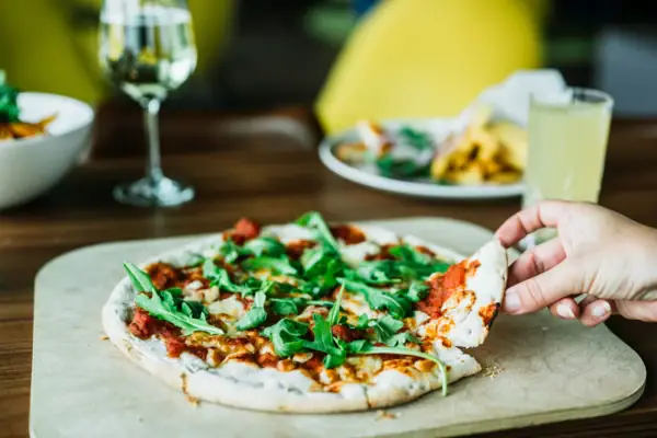 Eén hand houdt een pizza vast.