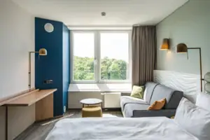 Kamers in het aja Warnemünde Een kamer met een bank, een bureau en een tweepersoonsbed.