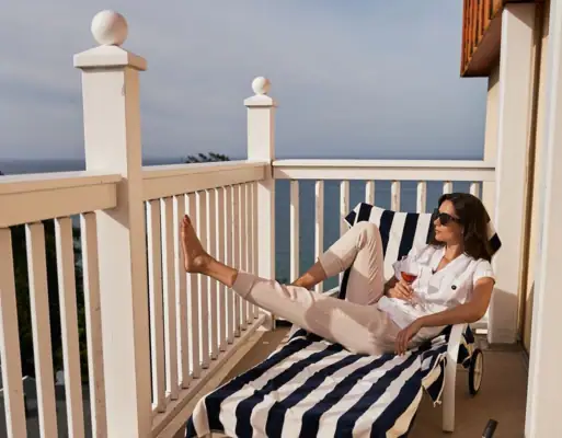 Balkon Noord Perd & Villa's Een vrouw zit op een stoel op een terras.