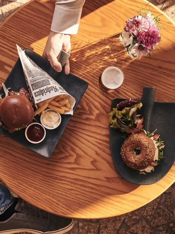 Een persoon houdt een bord eten vast aan een tafel.