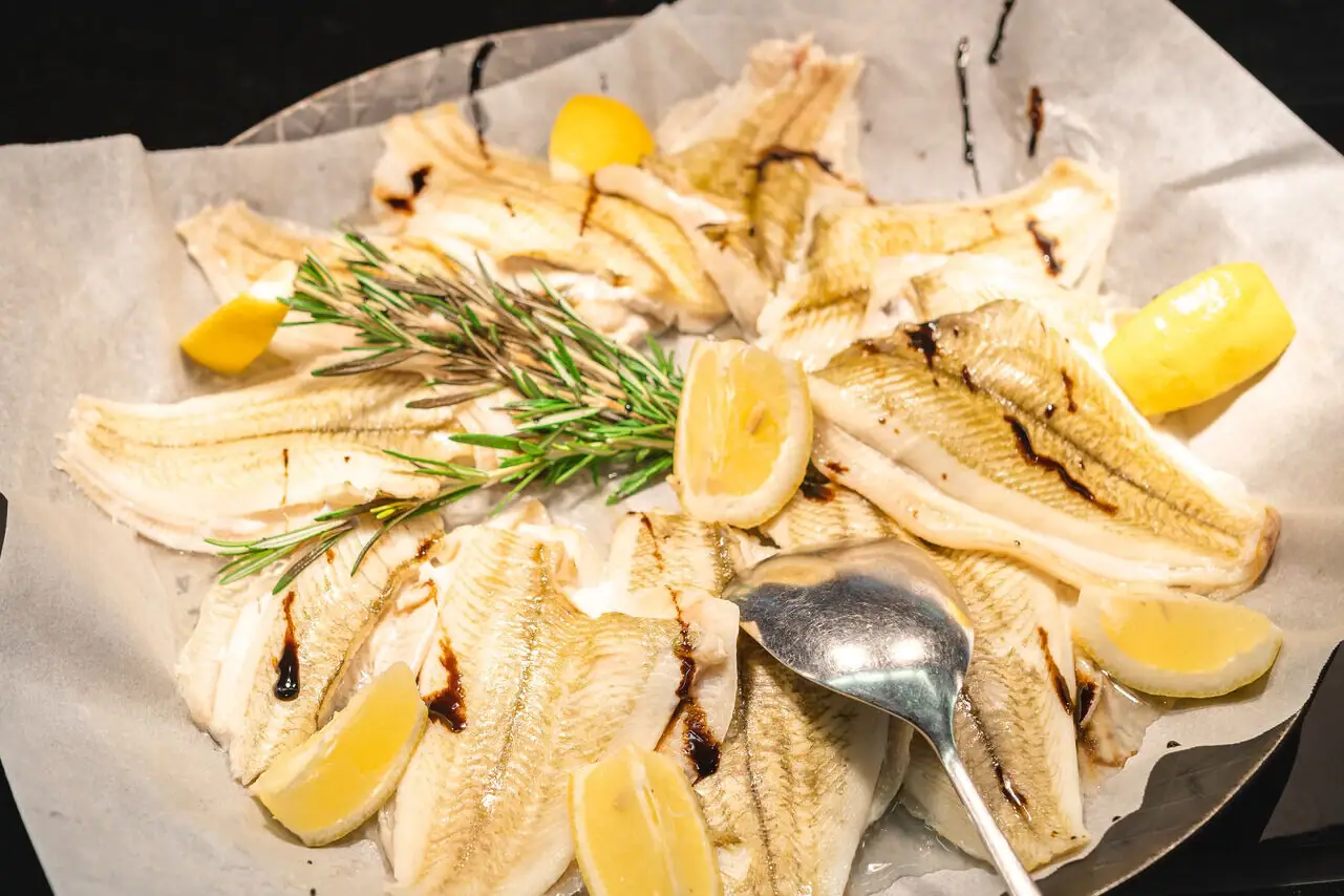 Vis Een bord met vis en citroenschijfjes, een lepel ernaast.