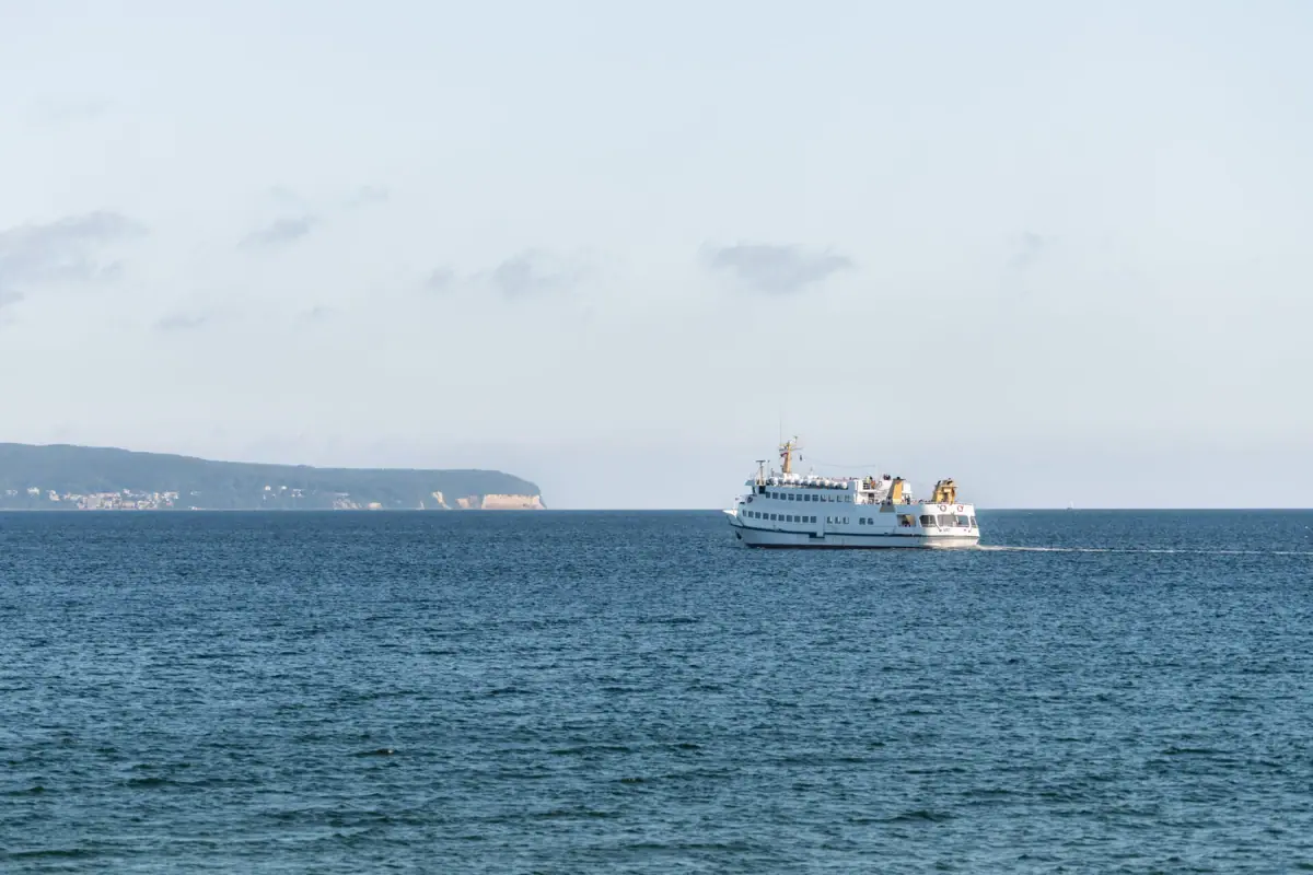 Een boot vaart op het water richting de krijtrotsen op Rügen.