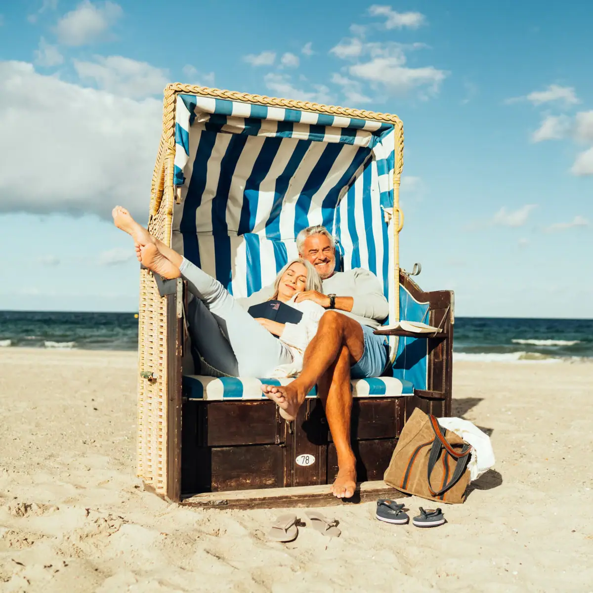 Een man en een vrouw zitten in een strandstoel op het strand.