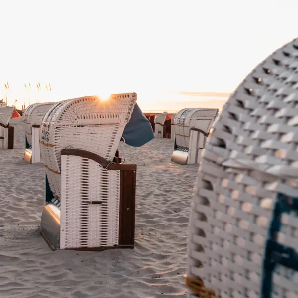 Eine Gruppe weißer Korbstühle am Strand.