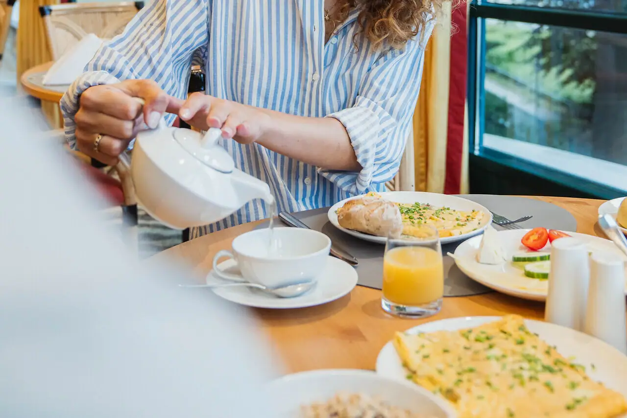 Thee Een vrouw schenkt thee in een kopje.