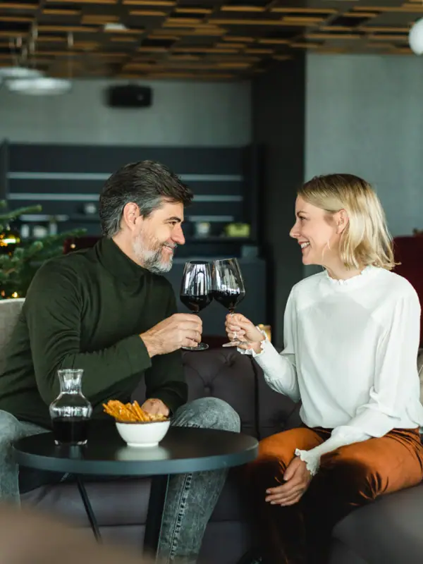 Bar met kerstboom Een man en een vrouw zitten op een bank wijn te drinken.