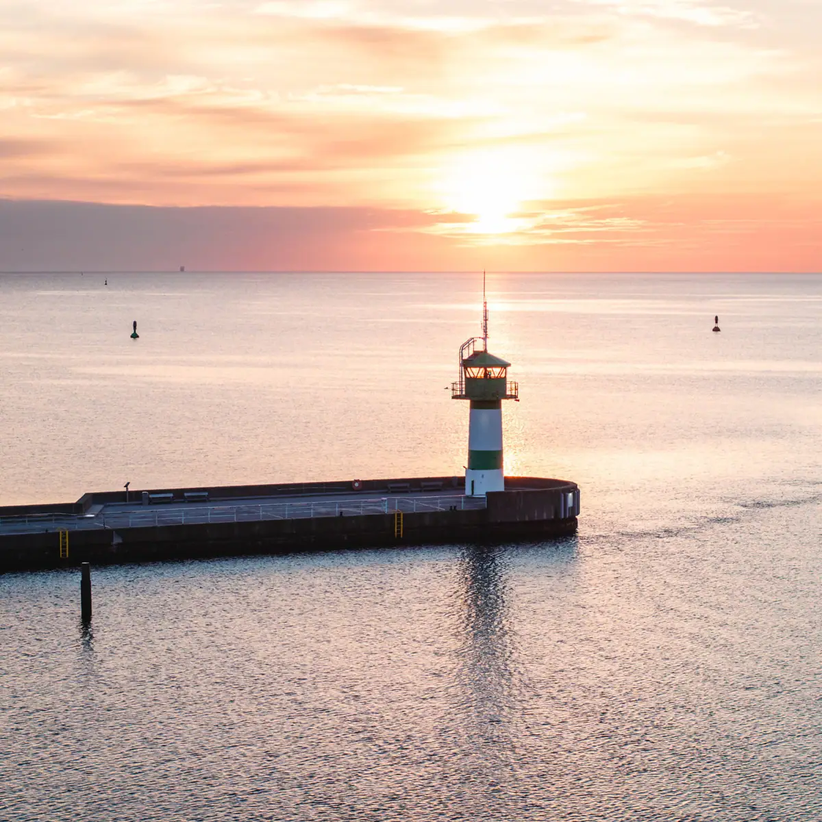 De groen-witte Nordermole met het water bij zonsopgang.