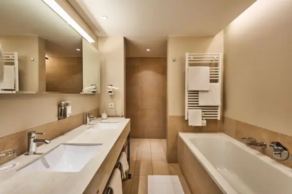 Badkamer met ligbad en wastafel, voorzien van kranen en tegels.