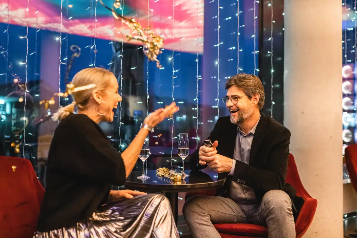 Een man en een vrouw zitten aan een tafel met glazen wijn.