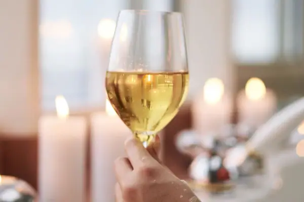 Eén hand houdt een wijnglas vast.