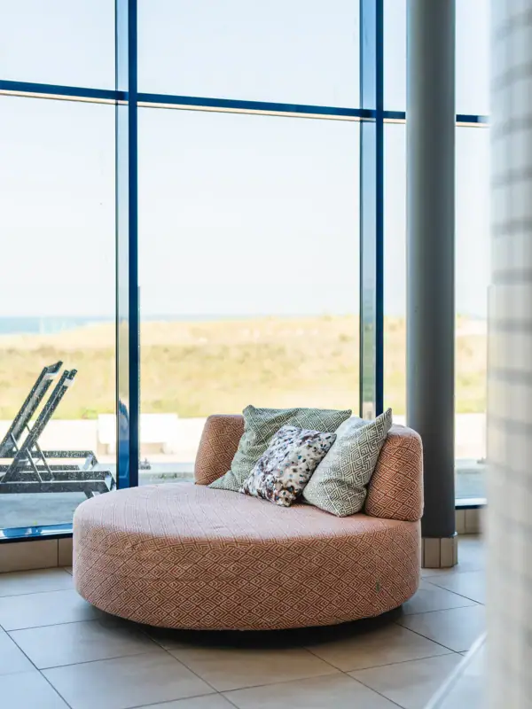 Ligstoel bij aja Warnemünde Ronde bank met kussens voor een raam.