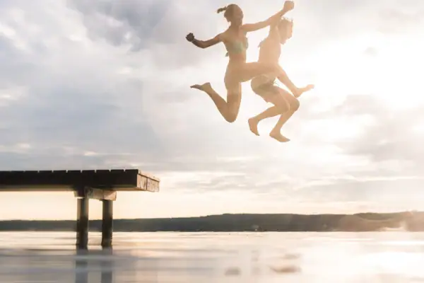 Sprong Scharmützelsee Een koppel springt in het water vanaf een steiger.