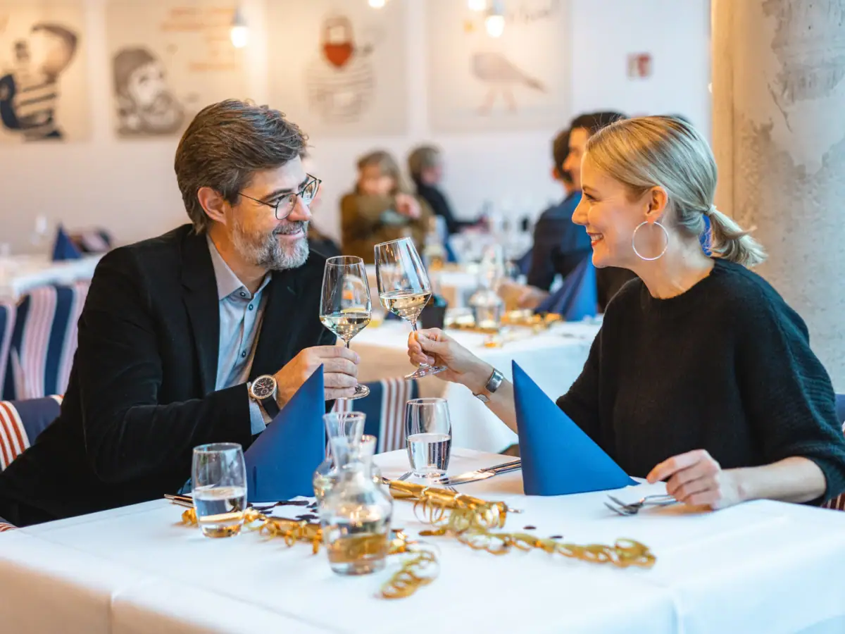 Een man en een vrouw zitten aan een tafel met glazen wijn.
