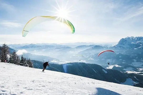 Groep mensen aan het paragliden op een besneeuwde berg.