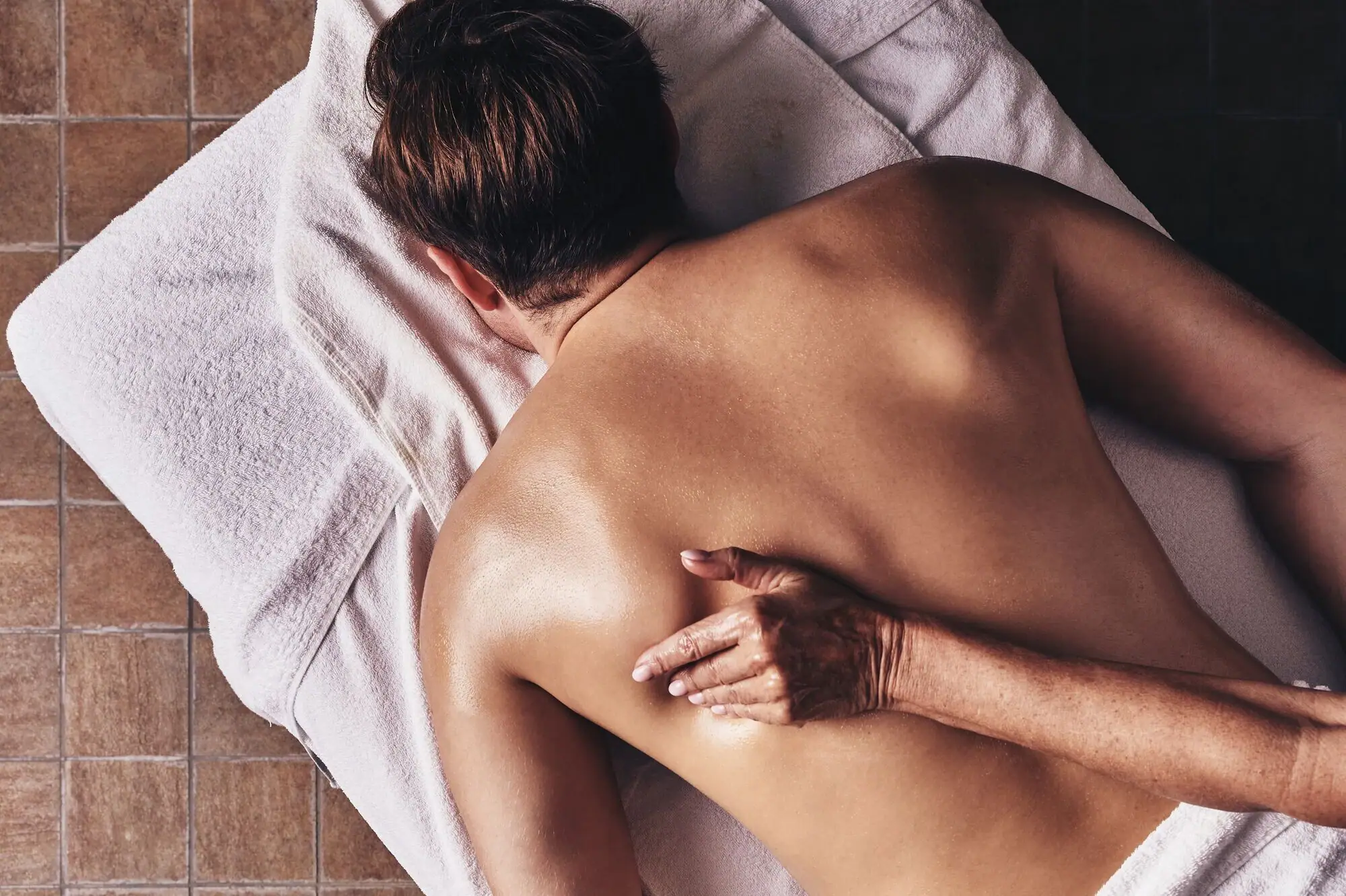 Persoon ligt op een handdoek met zijn rug naar de camera.