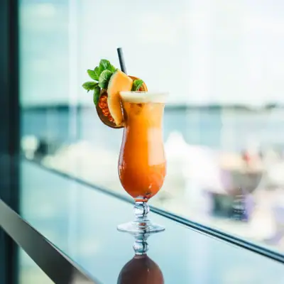 Een glas met een cocktail en citrusgarnituur op tafel.