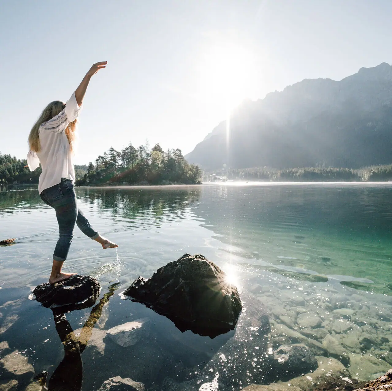 Eibsee Een vrouw balanceert op een steen bij de Eibsee in Garmisch-Partenkirchen.