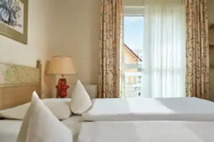 Tweepersoonskamer Landside Een bed met witte lakens en een lamp in een kamer met een raam.