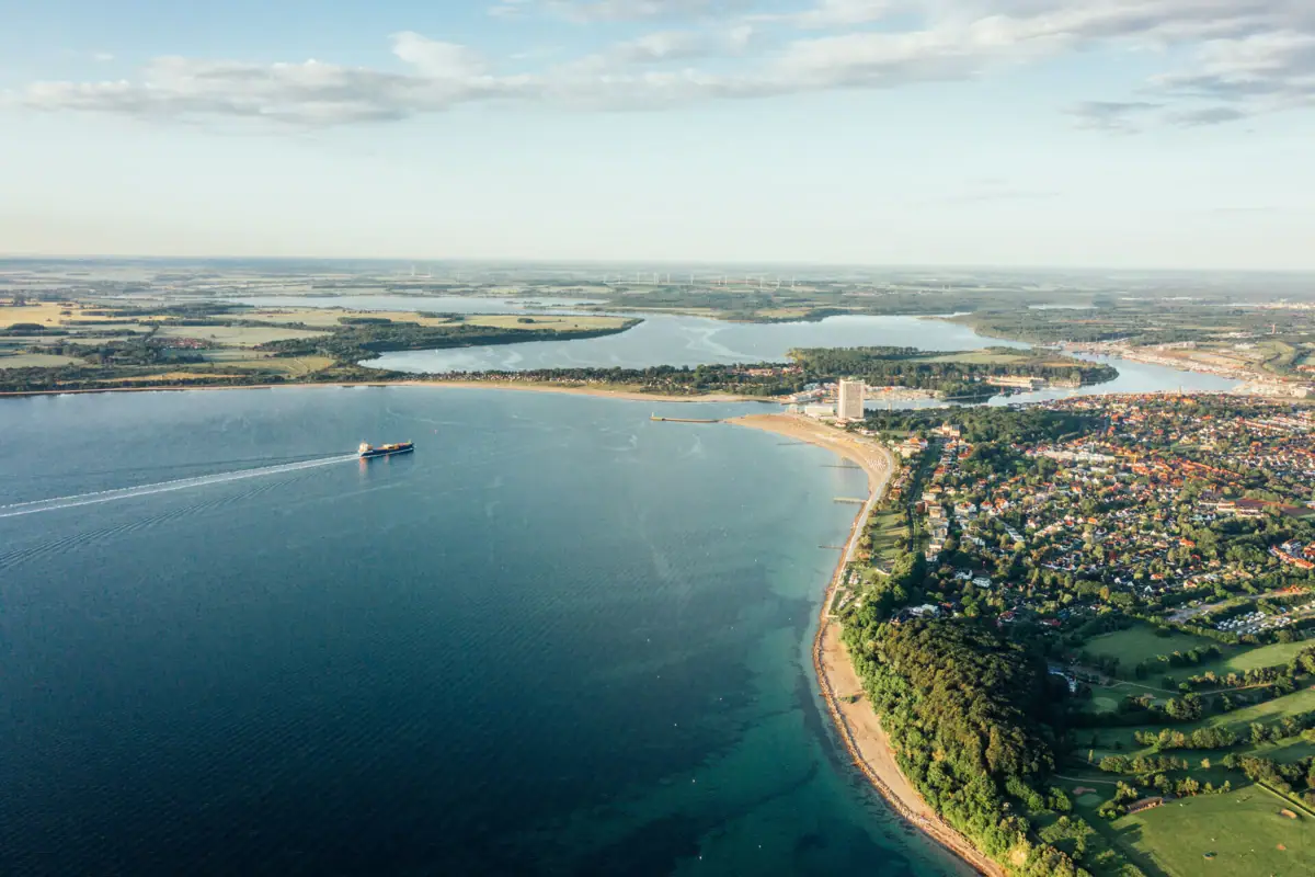 Luchtfoto van een waterlichaam en een kustplaats onder een bewolkte hemel.