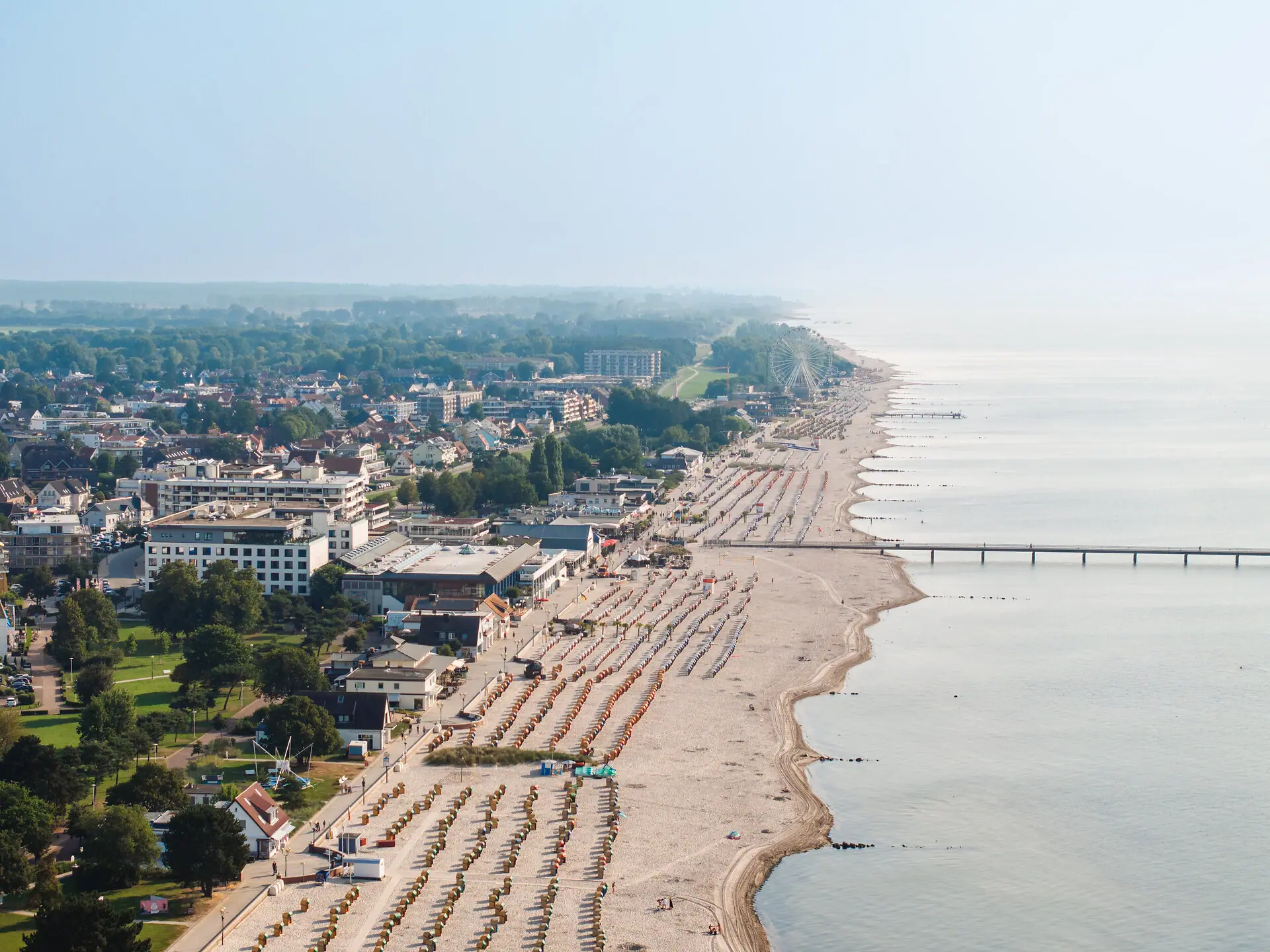 Een vogelperspectief van het strand met veel mensen en gebouwen.