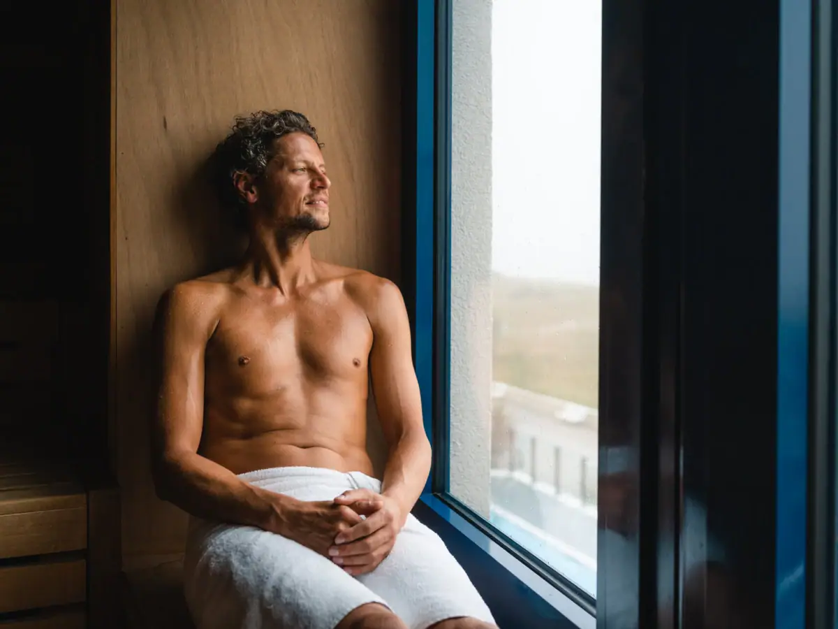 Sauna bij aja Warnemünde Een man zit op een vensterbank in de sauna.