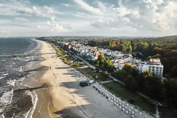 Bansin Strand met gebouwen en bomen op de voorgrond, lucht met wolken op de achtergrond.