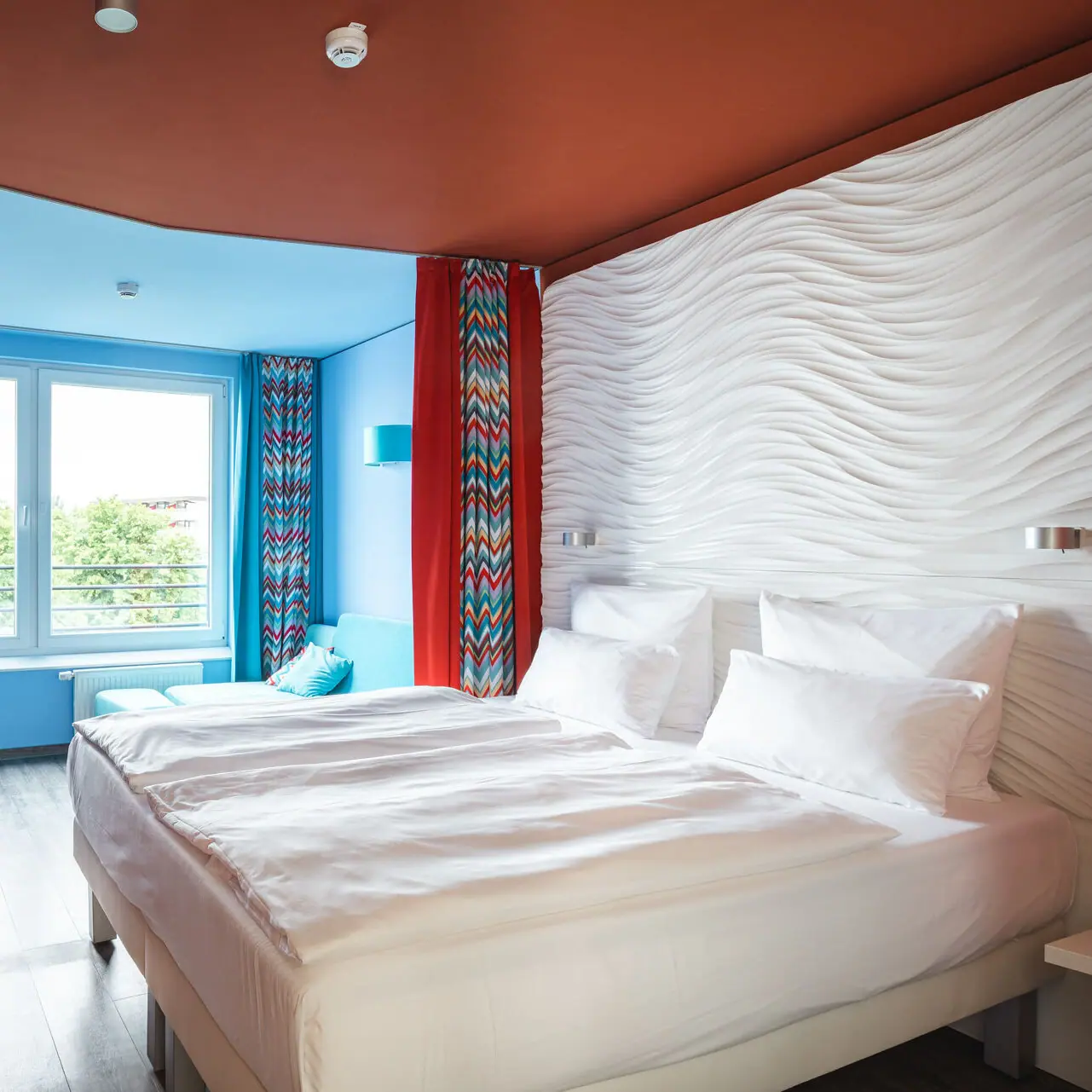 Een hotelkamer met een groot bed en rode gordijnen.