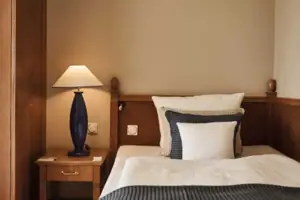 Tweepersoonskamer Een bed met een lamp op een nachtkastje.