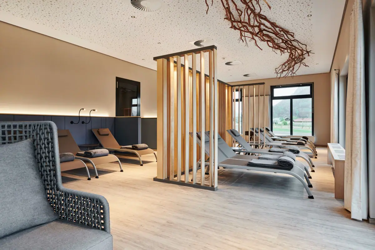 Ontspanningsruimte in het saunalandschap bij aja SPA Ruhpolding Een kamer met loungestoelen en een houten structuur.