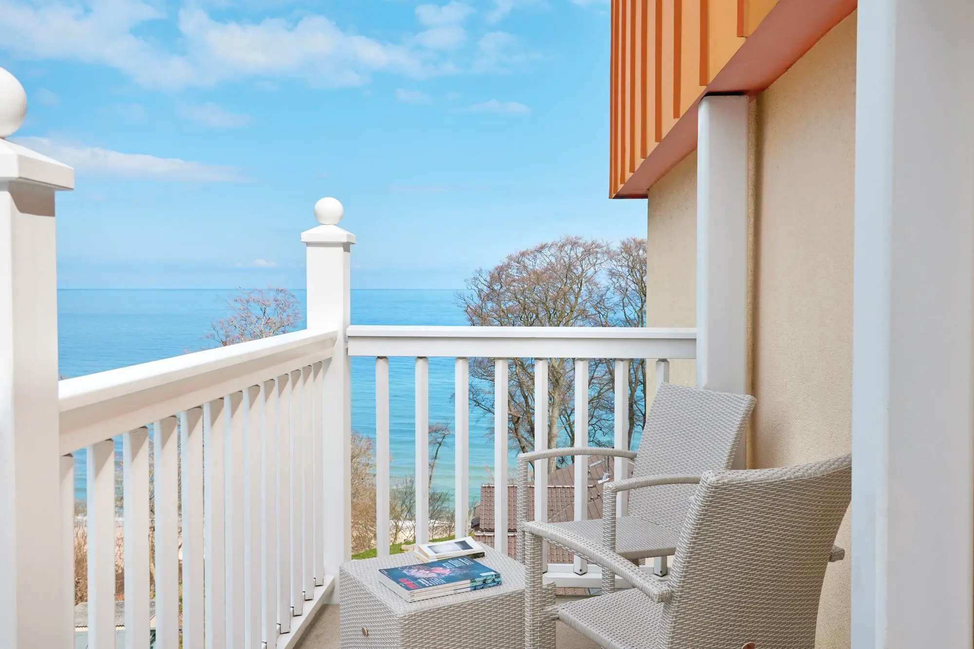 Een witte stoel en tafel op een balkon met uitzicht op zee.