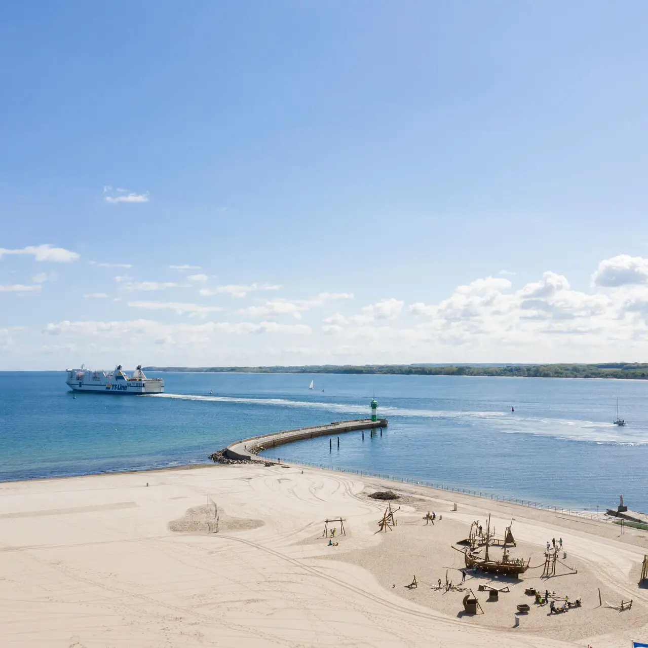 Een strand met een steiger en een boot in het water.