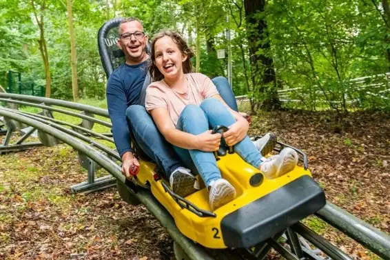 Een man en een vrouw in een achtbaan, allebei lachend.