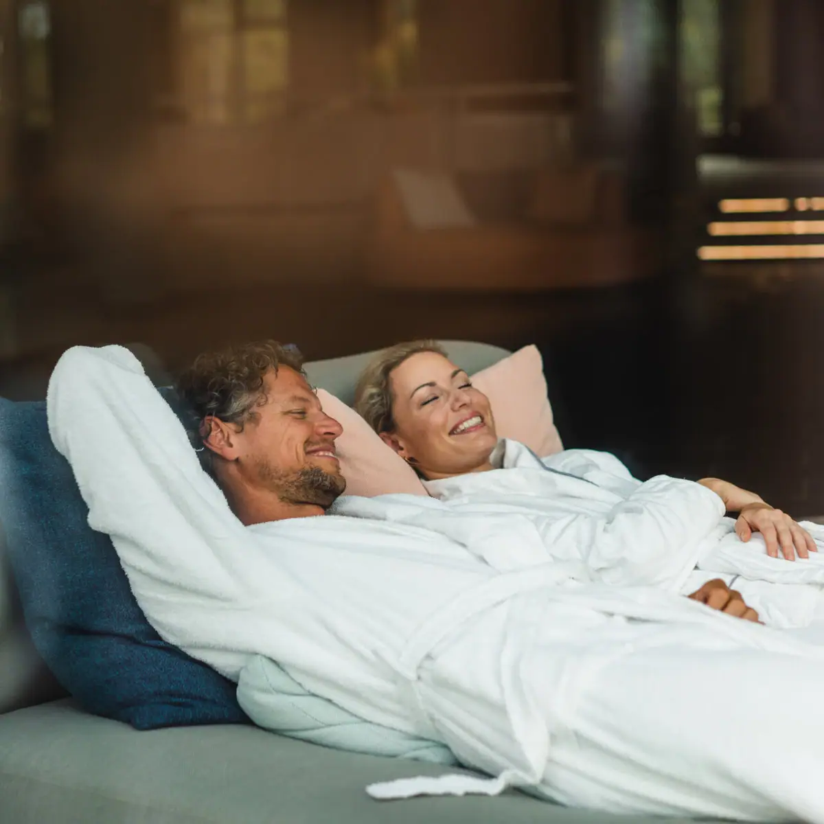 Een man en een vrouw liggen op een bank.