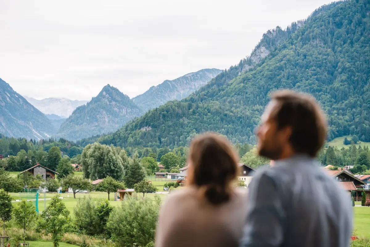 Uitzicht vanaf het balkon aja Ruhpolding Een man en een vrouw kijken naar bergen.
