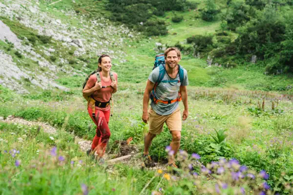 Wandelen Garmisch-Partenkirchen Een vrouw en een man wandelen over een klein pad door een berglandschap.