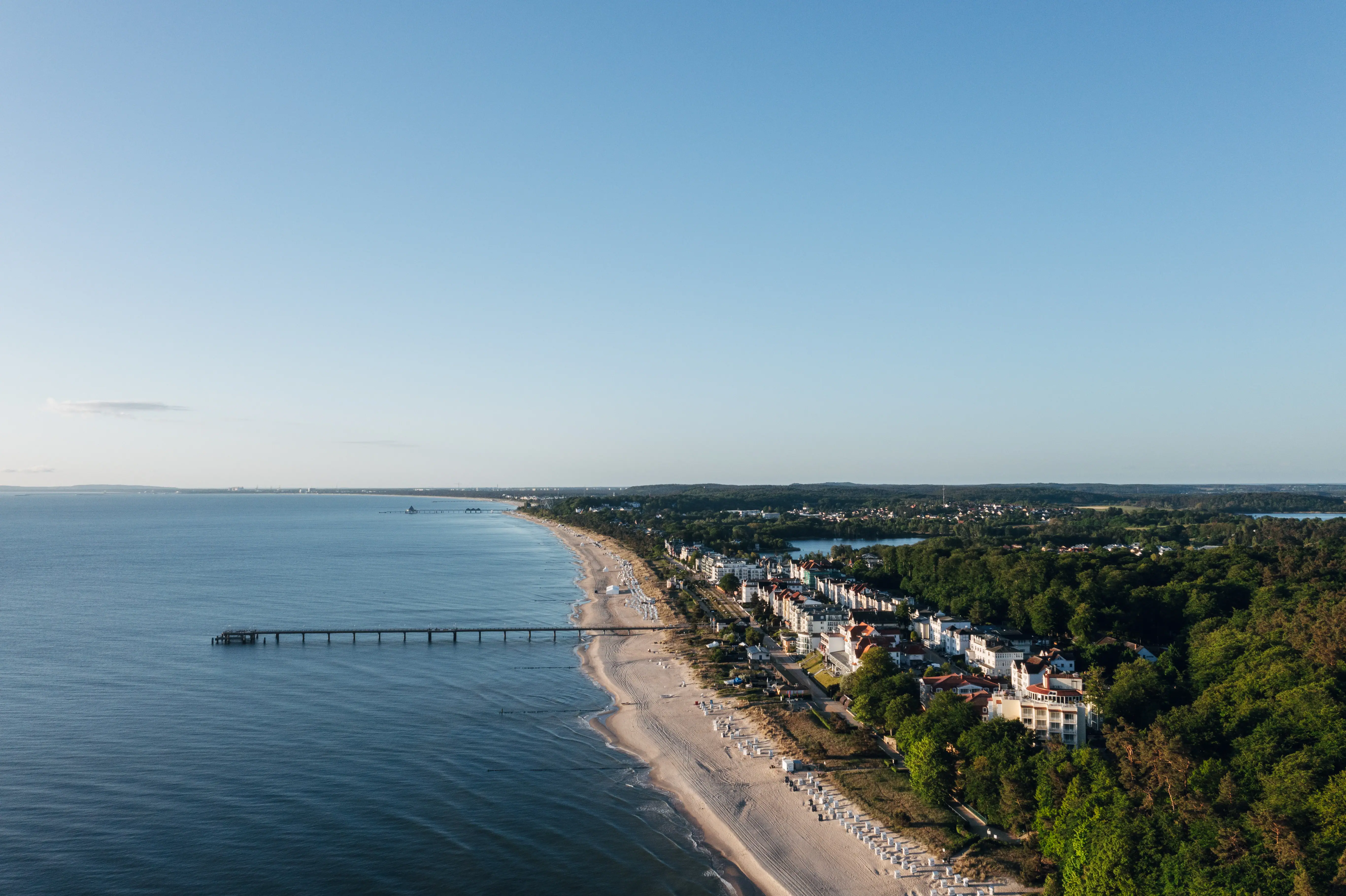 Strand met een pier en gebouwen op de achtergrond.