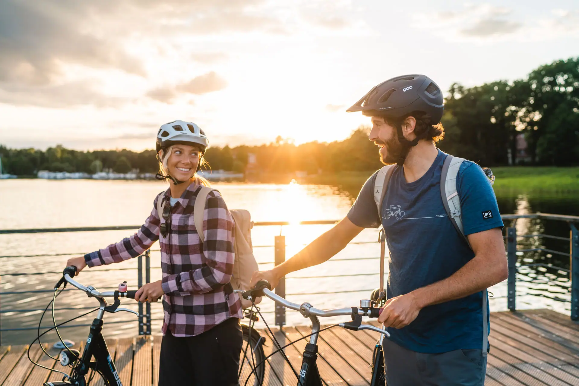 Een man en een vrouw met helmen en fietsen op een loopbrug.