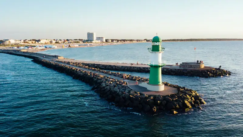 Groene en witte vuurtoren op rotsen in het water.