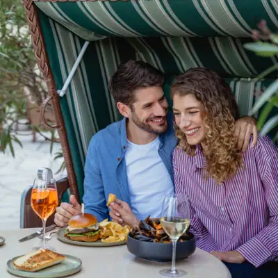Bistro & Bar Patio Een man en een vrouw zitten aan een tafel met eten en drinken.
