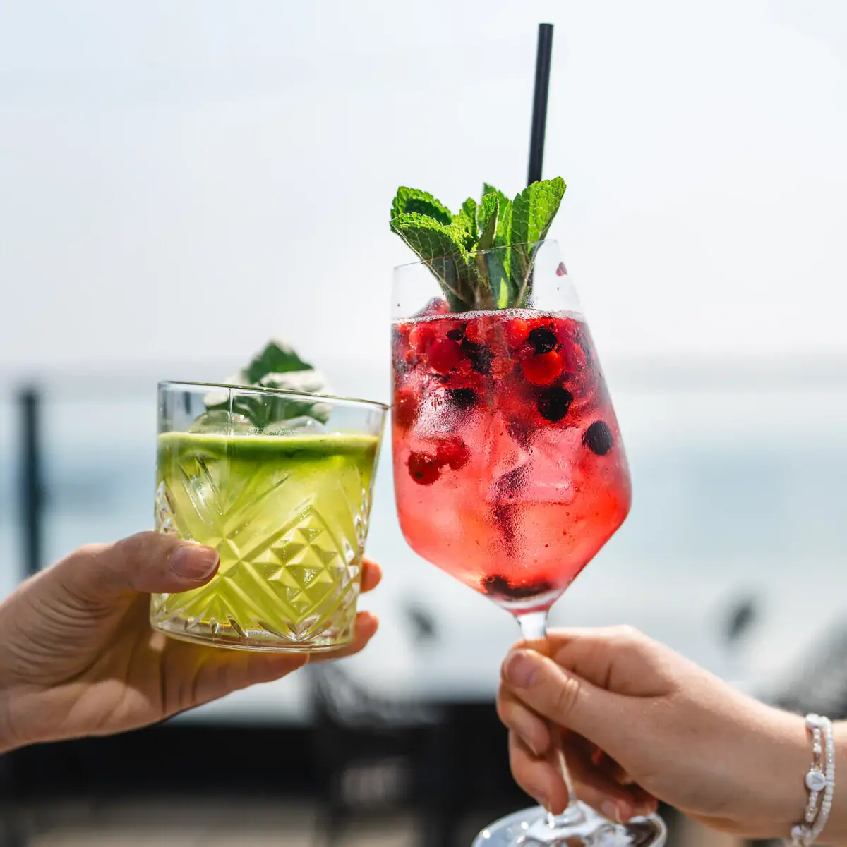 Cocktails Een paar handen die cocktails met fruitgarnering vasthouden.