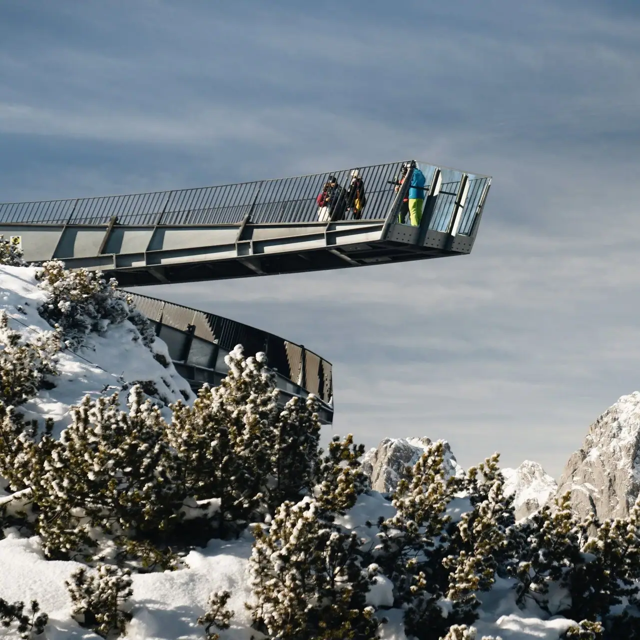 Alpspix Mensen steken een brug over op een besneeuwde berg.