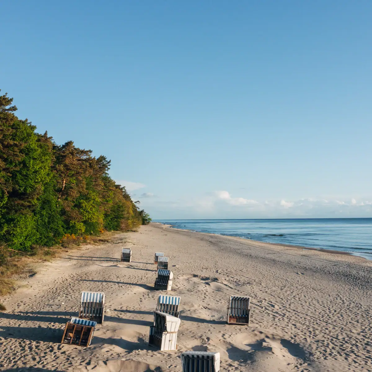 Stoelen op het strand met uitzicht op het water en de lucht.