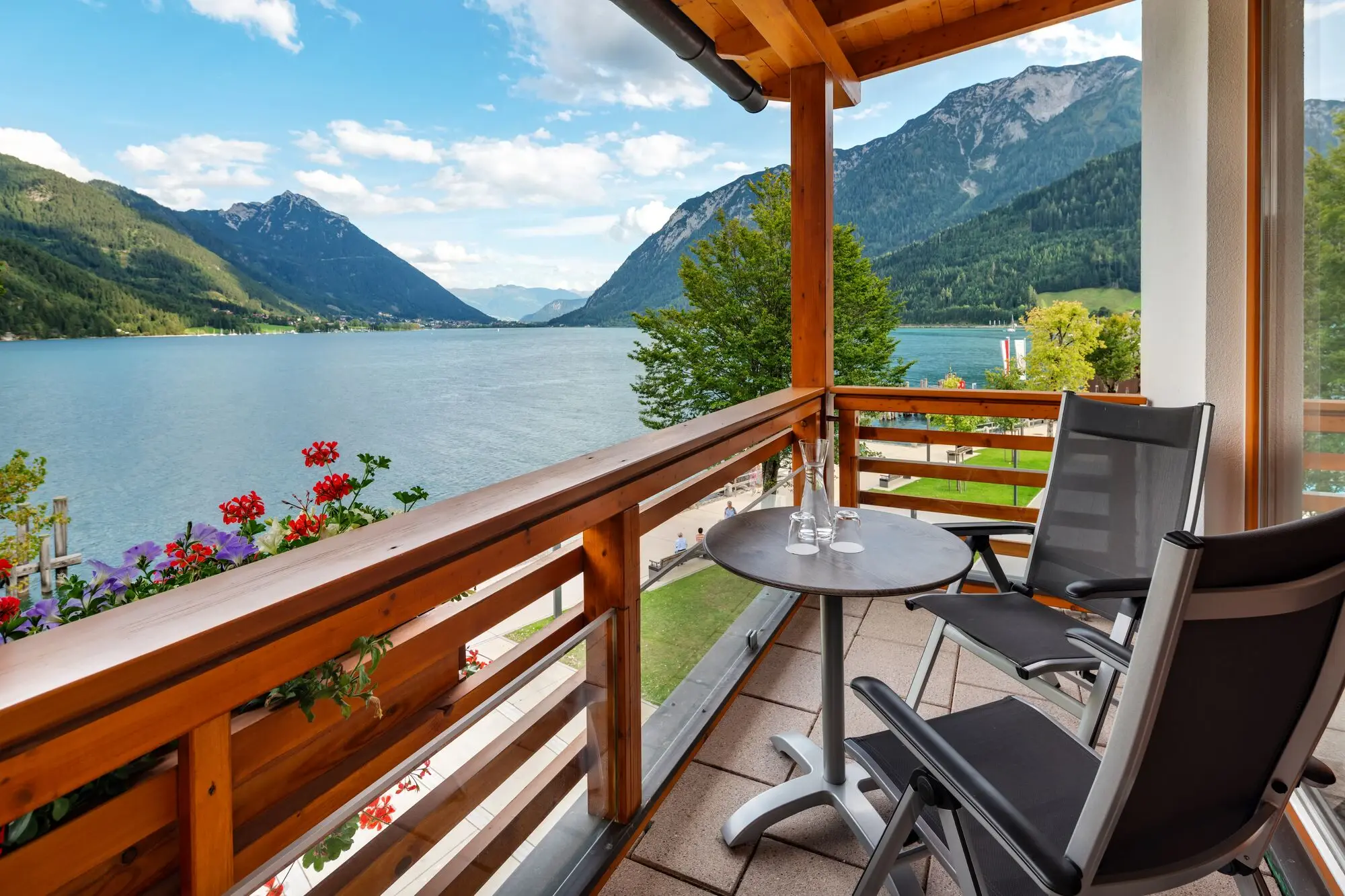 Ein Balkon mit Tisch und Stühlen mit Blick auf einen See.