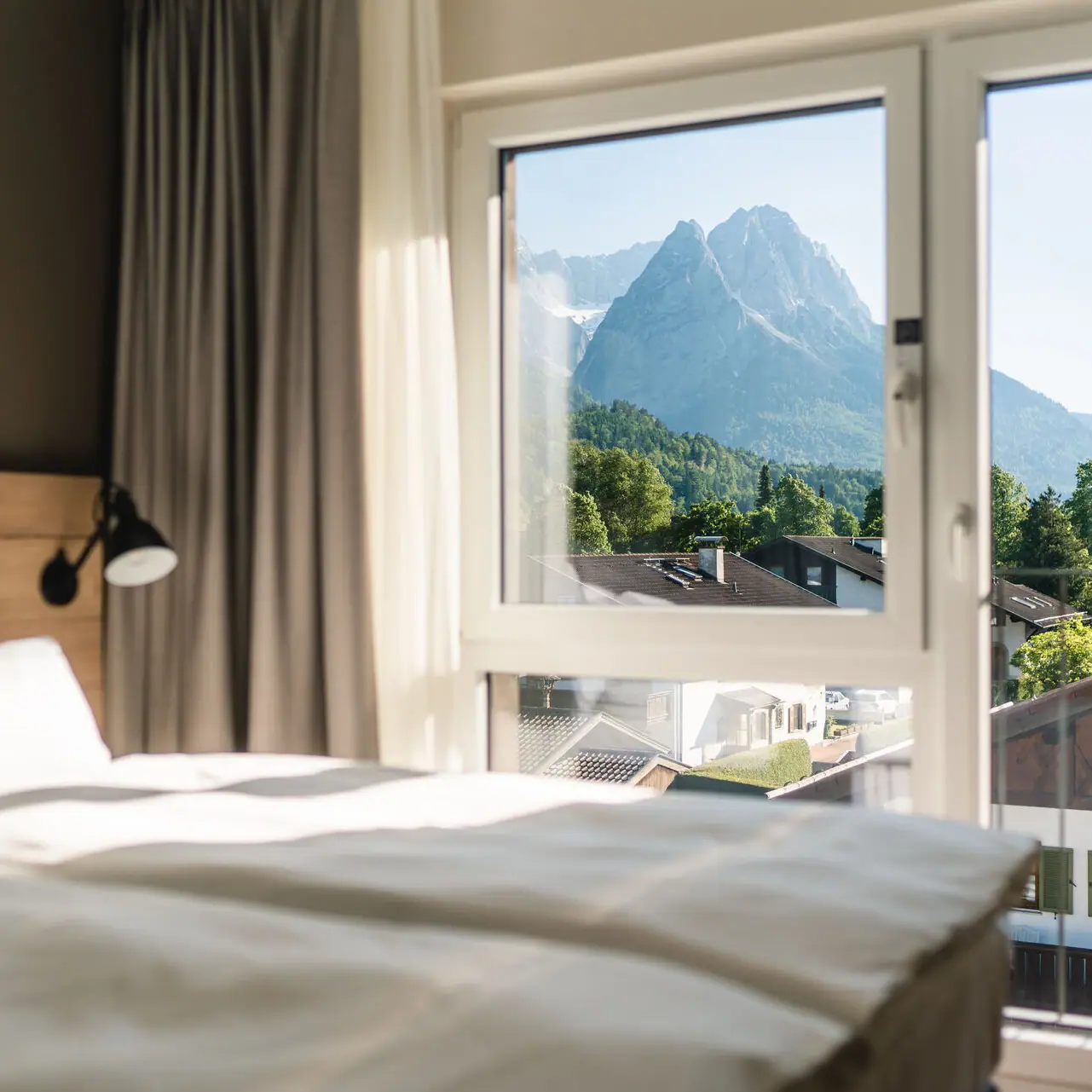 Vooruitzichten aja Garmisch Een hotelkamer in het aja Garmisch-Partenkirchen met een raam en uitzicht op de bergen.