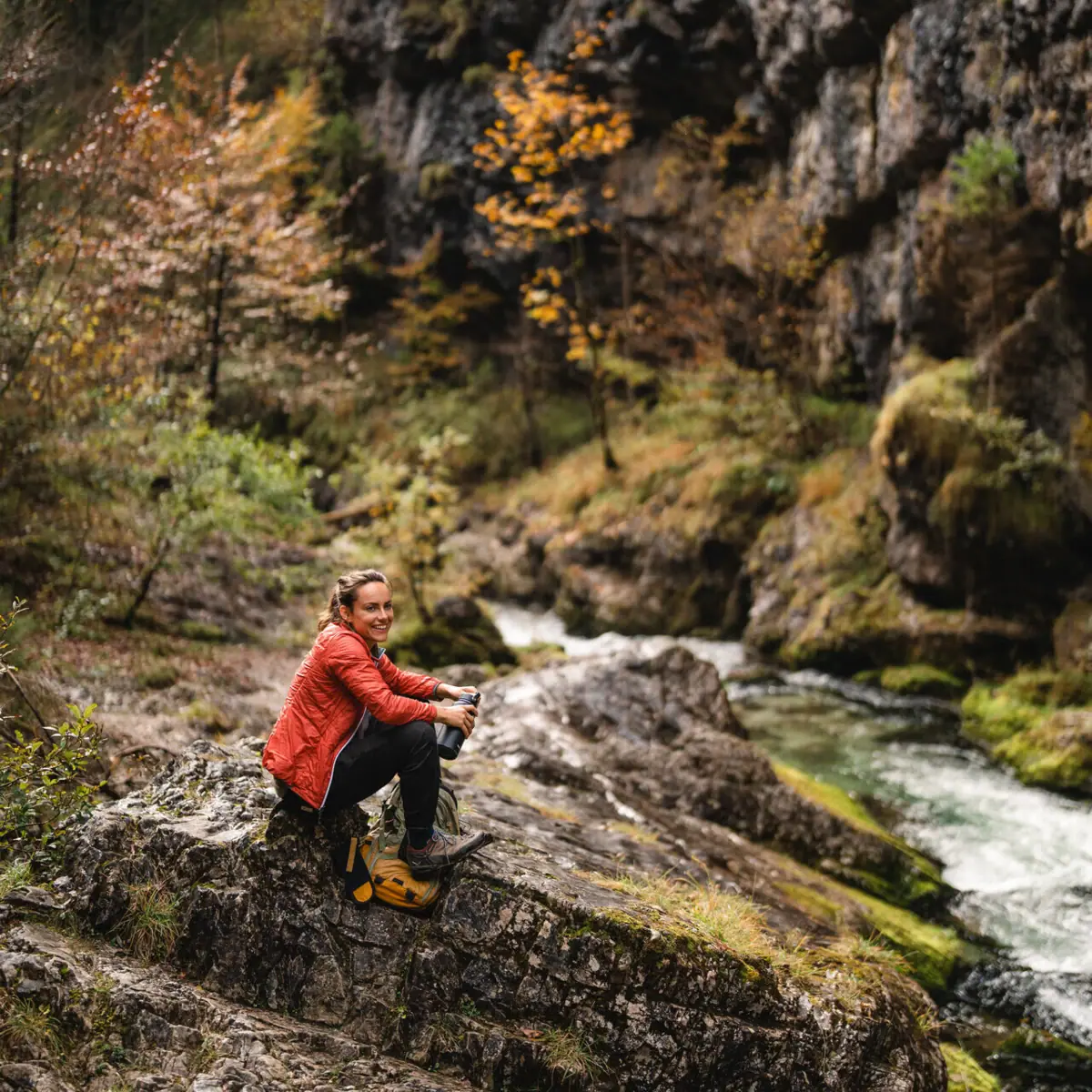 Weissenbach-kloof Een vrouw zit op een rots bij de rivier.